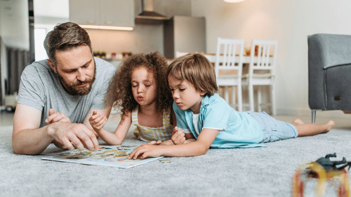 Father enjoying quality time on the floor with his two children, free from work interruptions, symbolizing the balance gained with a single-source property service provider.